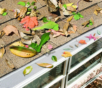 White PVC snap in gutter is installed on the roof and with several colorful leaves on it.